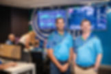 Jack and Pip standing in front of reporting monitors